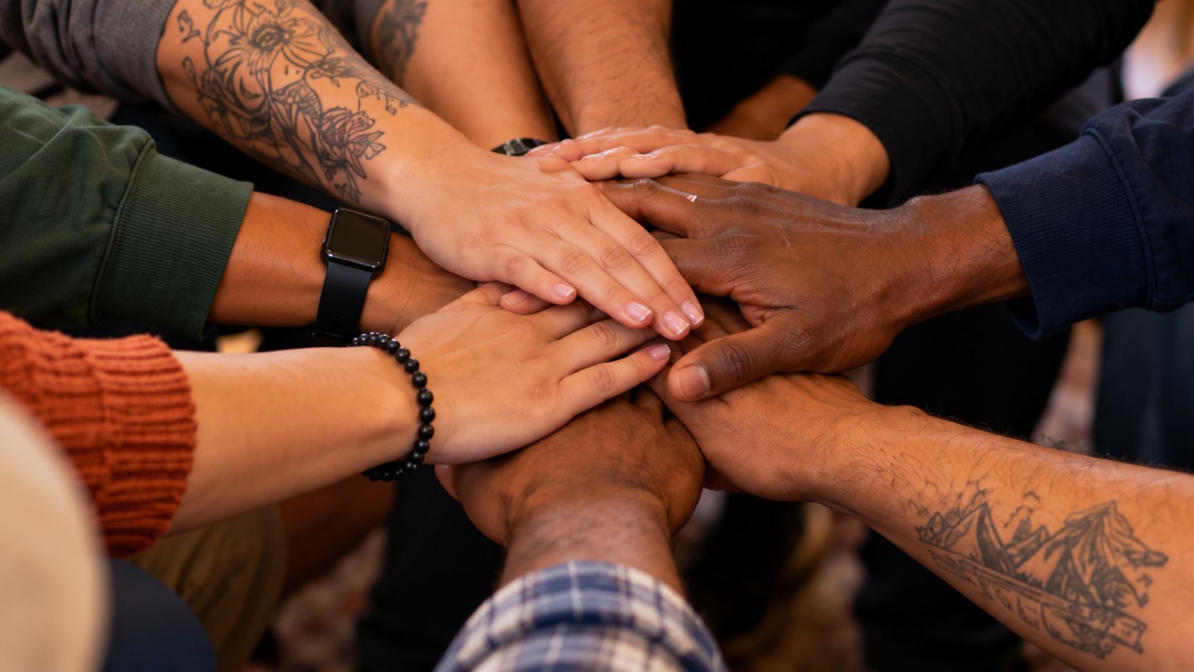 Illustration: many hands of different skin tones stacked together in a circle
